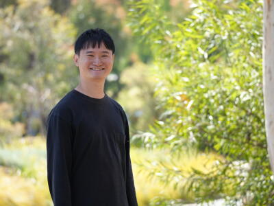 Man smiling next to a tree